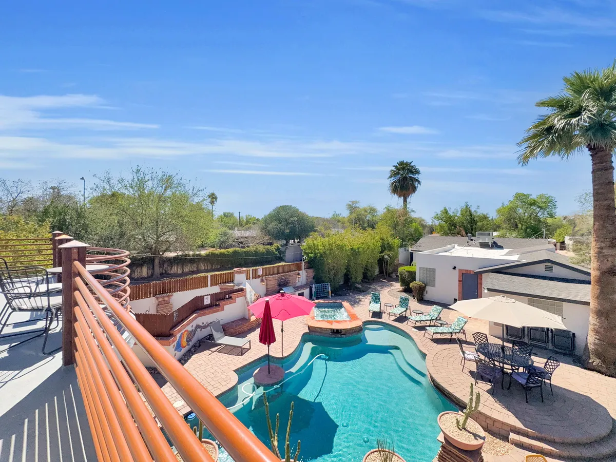 A serene outdoor space with a sparkling pool, attached spa, comfortable patio furniture, palm trees, and umbrellas offers a cheerful setting for swimming, sunbathing, or stargazing. The area is inviting at any time of day, from sunny afternoons to peaceful evenings.