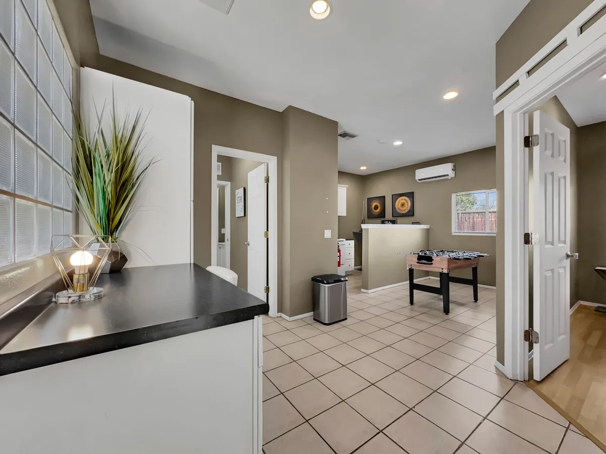 An open space combining a kitchen island and a foosball table, with artwork on the wall, blending culinary and recreational activities. The casual and welcoming mood encourages interactive family fun and shared experiences.