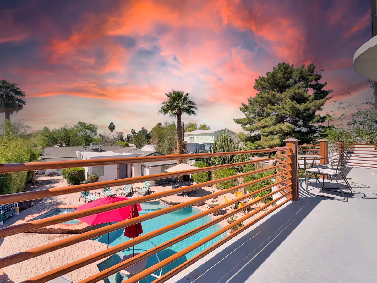 A cheerful exterior setting with a swimming pool surrounded by lounge chairs, decorative umbrellas, and palm trees. The ambiance is festive, perfect for relaxing or entertaining friends after exploring the city’s events and nightlife.