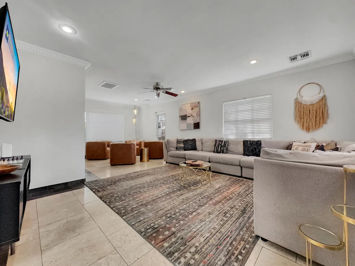 Another view of a cozy living area with a large sectional sofa, coffee table, wall-mounted television, and tasteful decor. The setup invites social gatherings, relaxed evenings, and casual game nights, reinforcing the sense of comfort and community.